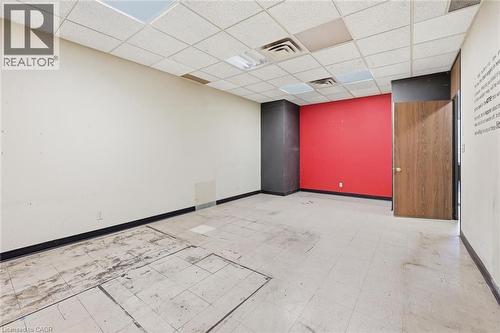 Spacious room featuring a vibrant accent wall, acoustic tile ceiling, recessed lighting, and wood-finish door - 869 Barton Street E, Hamilton, ON 