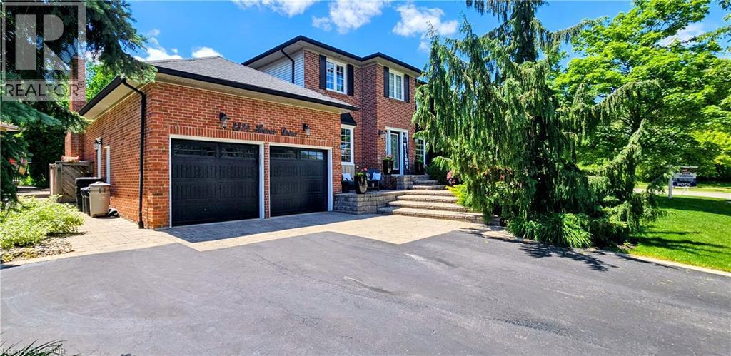 Brick exterior with a double garage featuring black doors, an asphalt driveway, and stone steps leading to the front entry - 2324 Homer Drive, Burlington, ON - Outdoor With Deck Patio Veranda