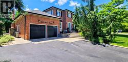 Brick exterior with a double garage featuring black doors, an asphalt driveway, and stone steps leading to the front entry -