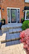 Brick facade featuring a black front door with decorative glass, two sidelights, and exterior sconces -
