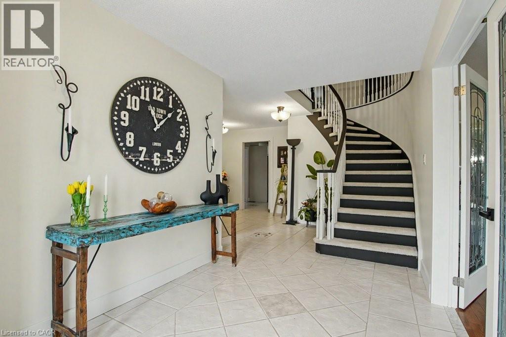 Foyer featuring a curved staircase with dark treads and white risers, white balusters, and a dark wood-finish handrail - 2324 Homer Drive, Burlington, ON - Indoor Photo Showing Living Room