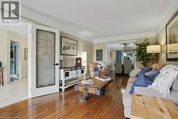 Living area featuring wood-finish flooring, crown molding, and a decorative frosted glass door -