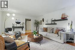Spacious living area featuring light-toned walls, crown molding, and wood-finish flooring -