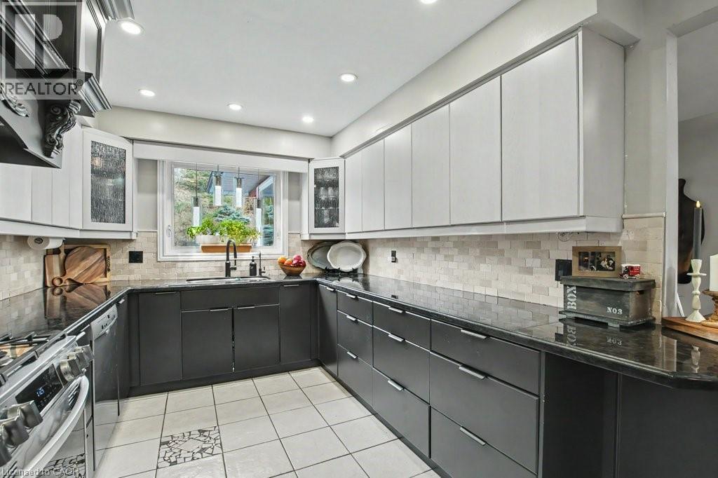 U-shaped kitchen featuring two-tone cabinetry, dark countertops, and a full tile backsplash - 2324 Homer Drive, Burlington, ON - Indoor Photo Showing Kitchen With Upgraded Kitchen
