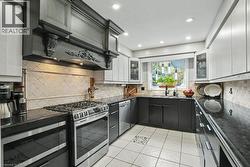 Kitchen featuring light and dark cabinetry, dark countertops, and a tiled backsplash -