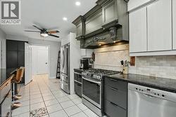 Modern kitchen with white tile flooring, dark granite countertops, and stainless steel appliances -