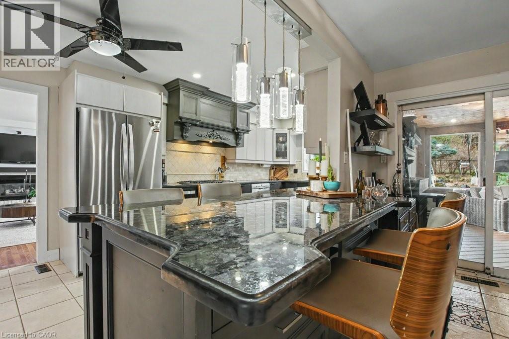 Kitchen island with a dark granite countertop and integrated seating - 2324 Homer Drive, Burlington, ON - Indoor Photo Showing Kitchen