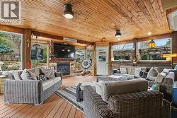 Spacious outdoor living area featuring a tongue-and-groove wood ceiling, wood-finish flooring, a built-in fireplace, and expansive windows -