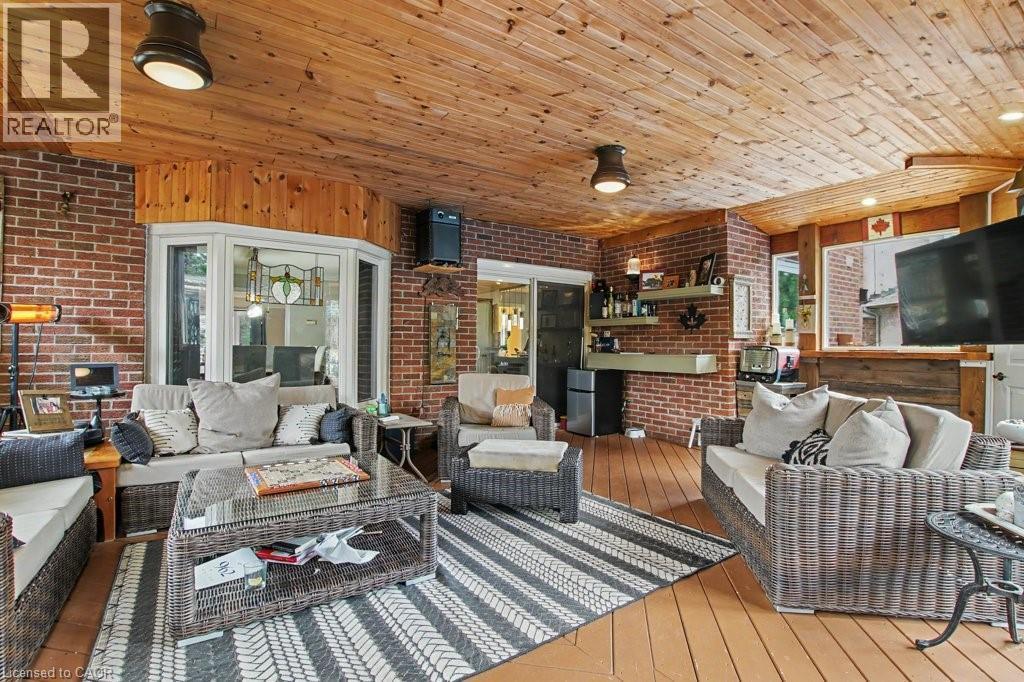 Expansive enclosed patio featuring a wood-finish ceiling, brick walls, bay window with stained glass detail, and wood-finish flooring - 2324 Homer Drive, Burlington, ON - Indoor Photo Showing Bedroom