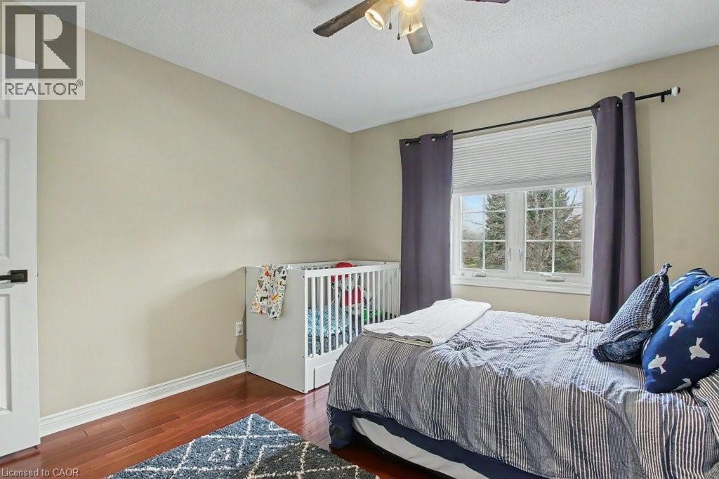 Bright room featuring wood-finish flooring, a double window with blinds, and a ceiling fan - 2324 Homer Drive, Burlington, ON - Indoor