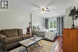 Spacious room with wood-finish flooring, a ceiling fan, and a double window with drapes -