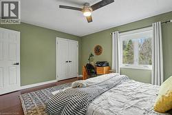 Spacious room with wood-finish flooring, a ceiling fan, and a large window -