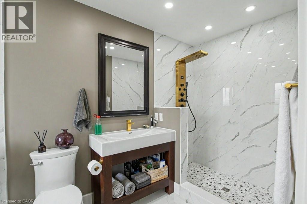 Contemporary bathroom featuring a dark wood-finish vanity with an integrated basin, a gold-tone faucet, and a framed mirror - 2324 Homer Drive, Burlington, ON - Indoor Photo Showing Bathroom