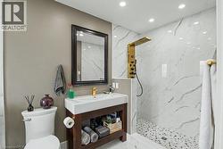 Contemporary bathroom featuring a dark wood-finish vanity with an integrated basin, a gold-tone faucet, and a framed mirror -