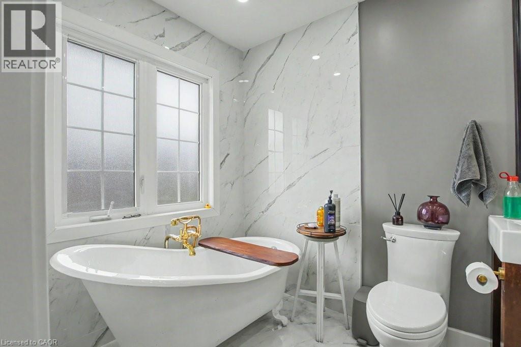 Freestanding porcelain bathtub with ornate gold-finish fixtures, complemented by white grid-patterned windows - 2324 Homer Drive, Burlington, ON - Indoor Photo Showing Gym Room