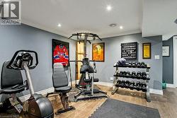 Dedicated exercise room featuring wood-finish flooring, recessed lighting, crown molding, and painted walls -