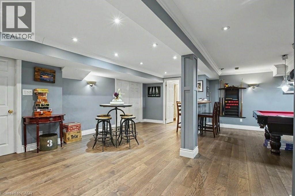 Spacious recreational room featuring wood-finish flooring, recessed lighting, and wall sconces - 2324 Homer Drive, Burlington, ON - Indoor Photo Showing Other Room