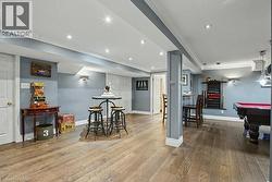 Spacious recreational room featuring wood-finish flooring, recessed lighting, and wall sconces -