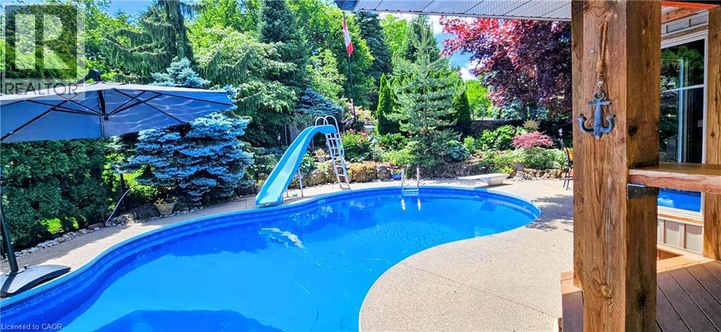 Outdoor swimming pool with a curved edge and integrated slide - 2324 Homer Drive, Burlington, ON - Outdoor With In Ground Pool With Backyard