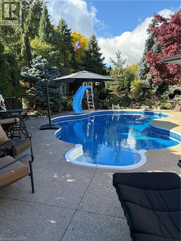 Irregularly shaped swimming pool featuring a blue water surface and a built-in spa - 2324 Homer Drive, Burlington, ON - Outdoor With In Ground Pool