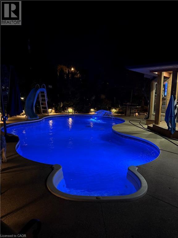 Freeform swimming pool with integrated lighting, surrounding concrete patio, and a built-in slide - 2324 Homer Drive, Burlington, ON - Outdoor With In Ground Pool With Backyard