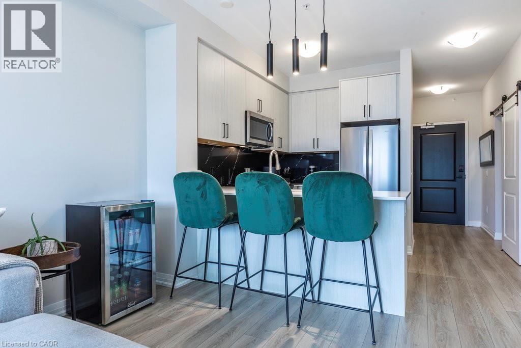 Modern kitchen with light-finish cabinetry, stainless steel appliances, and a dark stone backsplash - 120 Springvalley Crescent Unit# 208, Hamilton, ON - Indoor Photo Showing Other Room