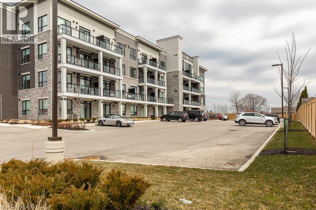 Multi-story building featuring brick and stone cladding, multiple balconies with glass railings, and expansive windows - 120 Springvalley Crescent Unit# 208, Hamilton, ON - Outdoor With Balcony With Facade