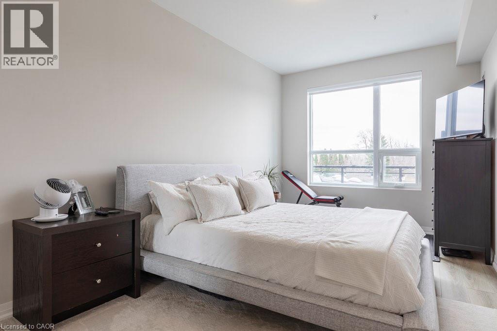 Bright bedroom featuring a large window, neutral wall tones, and light wood-finish flooring - 120 Springvalley Crescent Unit# 208, Hamilton, ON - Indoor Photo Showing Bedroom