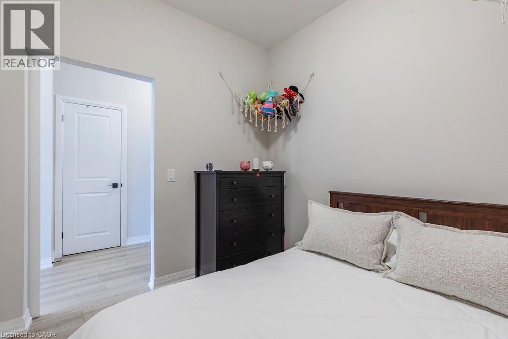 Bedroom featuring neutral wall colors, light wood-finish flooring, and a two-panel interior door with dark hardware - 120 Springvalley Crescent Unit# 208, Hamilton, ON - Indoor Photo Showing Bedroom