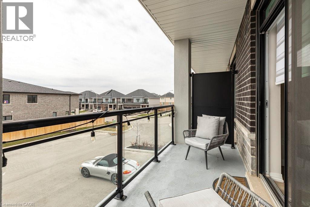 Outdoor balcony featuring a glass and metal railing, concrete flooring, and a brick exterior wall - 120 Springvalley Crescent Unit# 208, Hamilton, ON - Outdoor With Balcony With Exterior