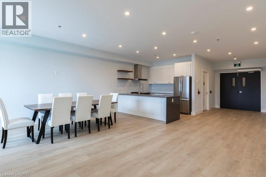 Open-concept living space featuring wood-finish flooring, recessed lighting, and a contemporary kitchen with white cabinetry, stainless steel appliances, and a central island with a sink - 120 Springvalley Crescent Unit# 208, Hamilton, ON - Indoor