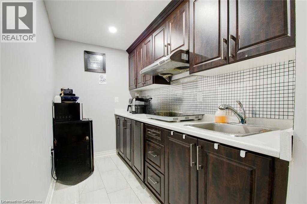 Kitchen with light countertops, dark brown cabinetry, under cabinet range hood, and tasteful backsplash - 49 Scots Pine Trail, Kitchener, ON - Indoor Photo Showing Kitchen