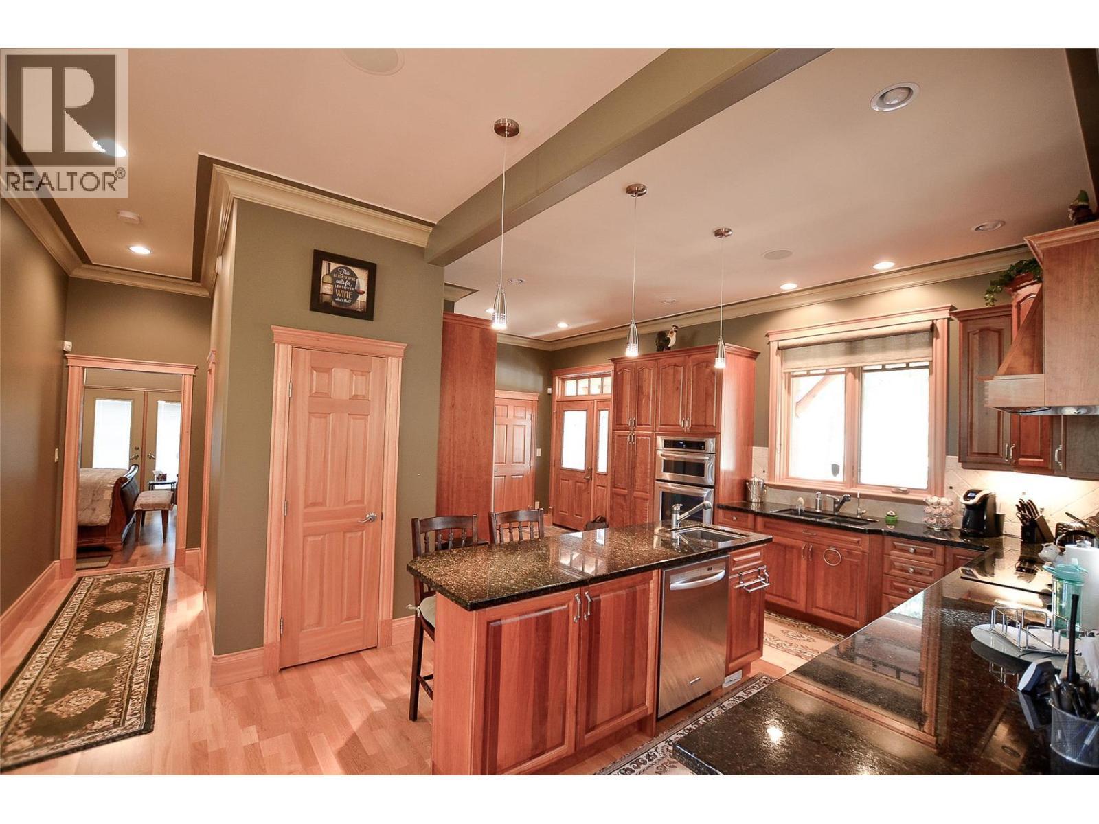 Pantry door and down the hall is the powder room, and primary bedroom with full ensuite. - 19-3453 Cessna Road, Enderby, BC - Indoor Photo Showing Kitchen