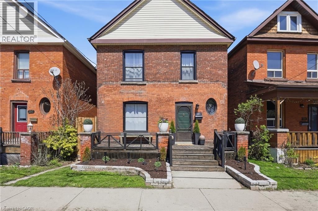 Brick facade residential property featuring a covered front porch with dark wood railings - 361 Cumberland Avenue, Hamilton, ON - Outdoor With Deck Patio Veranda With Exterior