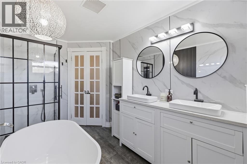 Modern bathroom featuring a freestanding soaking tub, a black-framed glass shower enclosure, and a double vanity with vessel sinks - 361 Cumberland Avenue, Hamilton, ON - Indoor