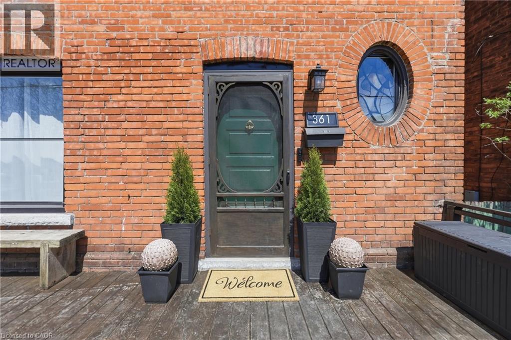 Brick facade featuring a recessed entry with an ornate screen door and an oval window - 361 Cumberland Avenue, Hamilton, ON - Outdoor With Exterior