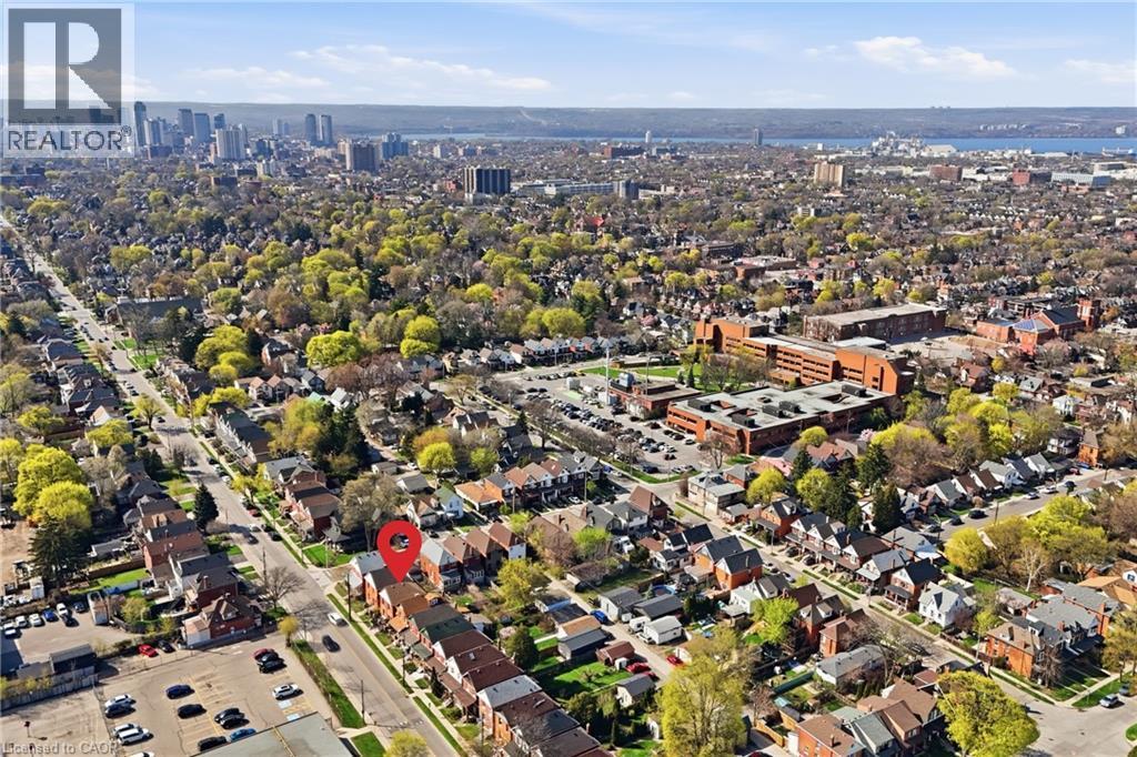 Aerial perspective of a tree-lined residential area with urban architecture, a distant cityscape, a substantial body of water, and surrounding green spaces under a clear sky - 361 Cumberland Avenue, Hamilton, ON - Outdoor With View