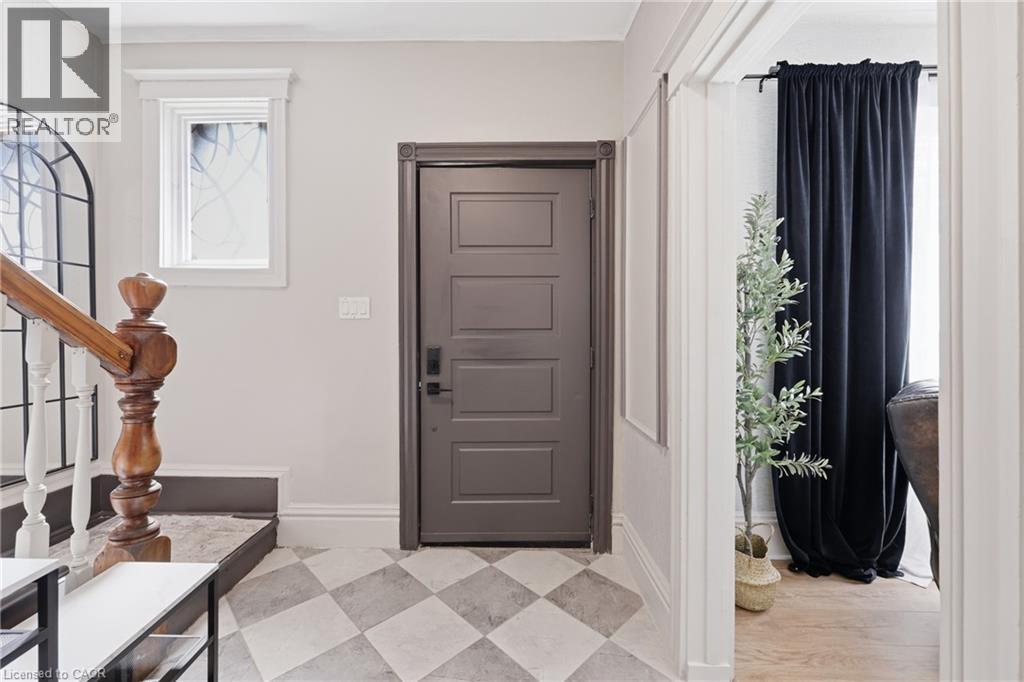 Foyer featuring diamond-patterned floor tiles, a five-panel entry door with dark hardware, and a wood banister with white balusters - 361 Cumberland Avenue, Hamilton, ON - Indoor Photo Showing Other Room