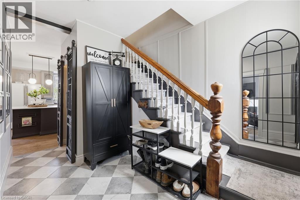 Staircase with wood balustrade and white risers, framed by a full-length arched mirror - 361 Cumberland Avenue, Hamilton, ON - Indoor Photo Showing Other Room