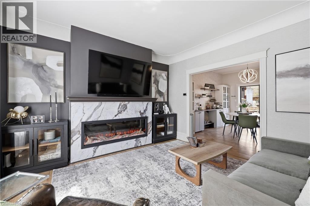 Living area featuring a floor-to-ceiling accent wall with a rectangular fireplace set into a marble-finish surround - 361 Cumberland Avenue, Hamilton, ON - Indoor Photo Showing Living Room With Fireplace