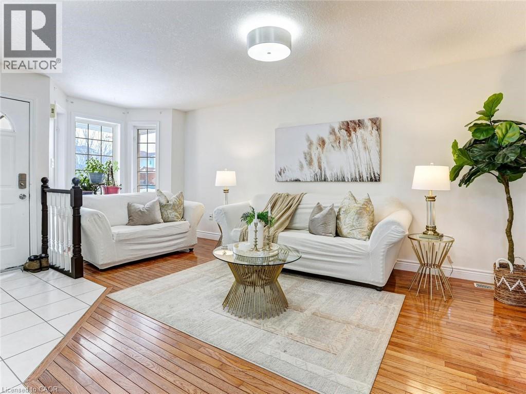 Bright living area featuring wood-finish flooring, white walls, a bay window with multiple panes, a white ceiling, and a flush mount light fixture - 154 Deerpath Drive, Guelph, ON - Indoor Photo Showing Living Room