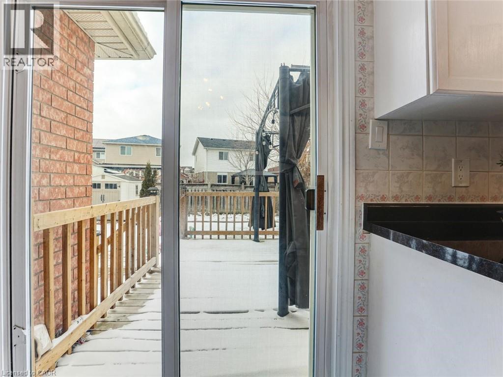 Sliding glass door opens to an exterior deck featuring a wooden railing and brick siding - 154 Deerpath Drive, Guelph, ON - With Exterior