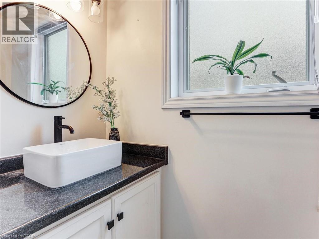 Bathroom vanity featuring a rectangular vessel sink, dark countertop, and white cabinetry with dark hardware - 154 Deerpath Drive, Guelph, ON - Indoor Photo Showing Bathroom