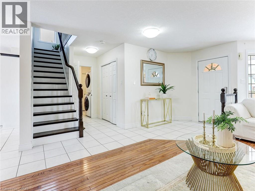 Bright entryway with tile flooring, featuring a staircase with dark treads and a wood-finish handrail - 154 Deerpath Drive, Guelph, ON - Indoor Photo Showing Other Room