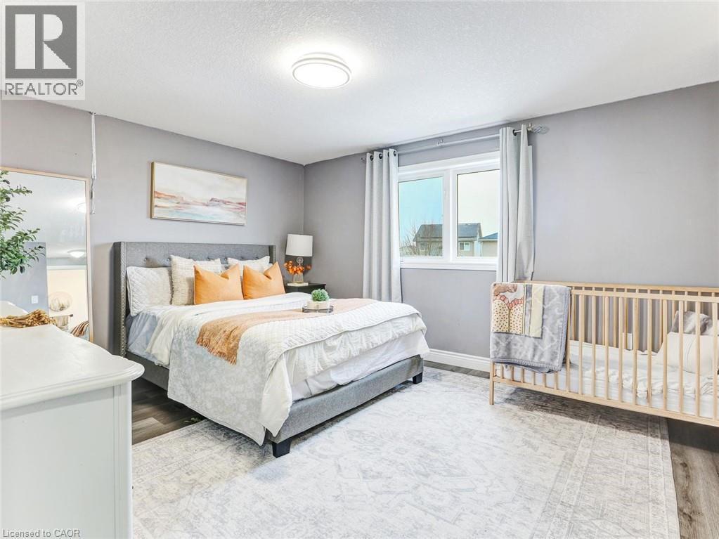 Bedroom featuring wood-finish flooring, a contemporary ceiling light fixture, and a window with curtains - 154 Deerpath Drive, Guelph, ON - Indoor Photo Showing Bedroom