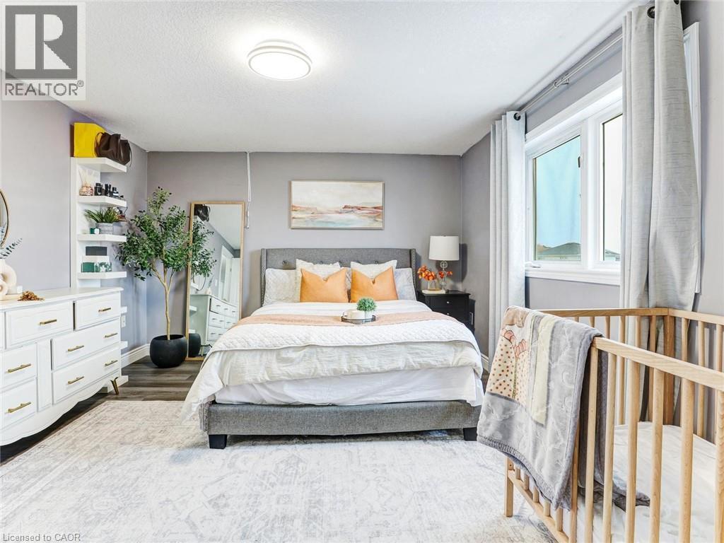 Spacious bedroom featuring light gray walls, a large window with drapes, wood-finish flooring, and a decorative area rug - 154 Deerpath Drive, Guelph, ON - Indoor Photo Showing Bedroom