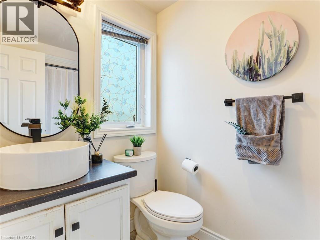 Bathroom featuring a round vessel sink with a black faucet, white cabinetry with dark hardware, and a dark countertop - 154 Deerpath Drive, Guelph, ON - Indoor Photo Showing Bathroom