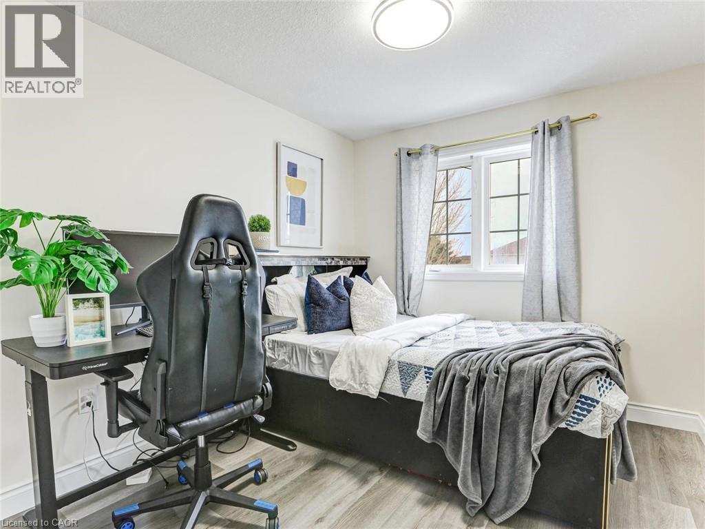 Bright bedroom featuring light-toned walls, wood-finish flooring, a window with natural light, and a flush-mount ceiling light fixture - 154 Deerpath Drive, Guelph, ON - Indoor Photo Showing Bedroom