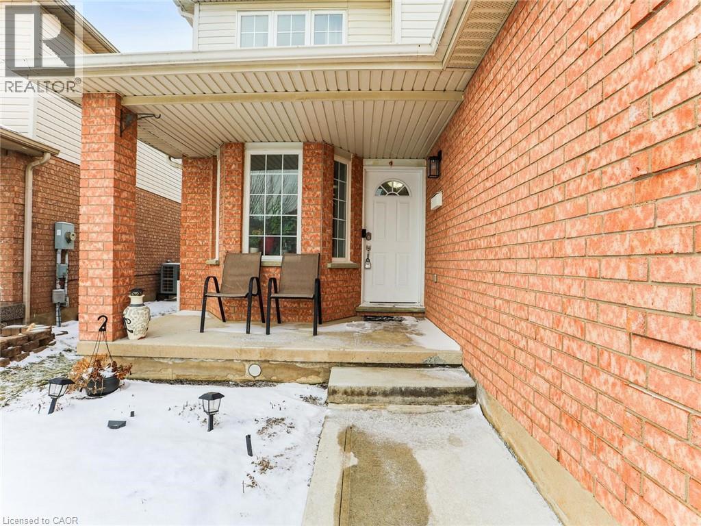 Brick facade with a covered porch featuring two brick columns, a white front door with an arched window, and a bay window - 154 Deerpath Drive, Guelph, ON - Outdoor With Exterior
