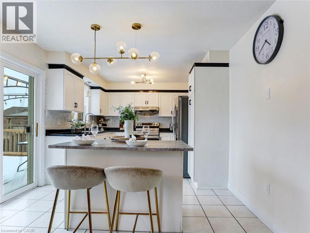 Modern kitchen featuring white cabinetry with black trim, a central island with bar seating, and a sliding glass door - 154 Deerpath Drive, Guelph, ON - Indoor Photo Showing Kitchen With Upgraded Kitchen